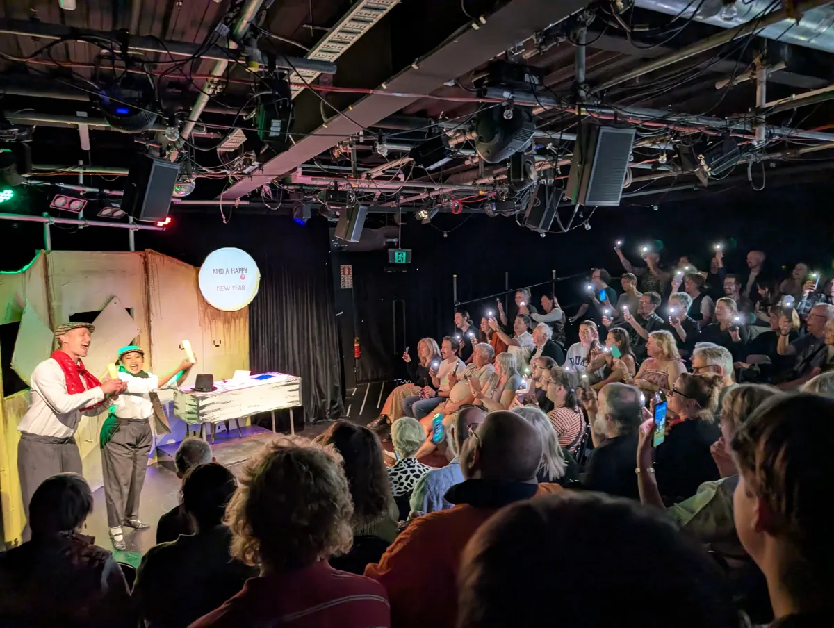 Performers and audience members holding lights during A Christchurch Carol
