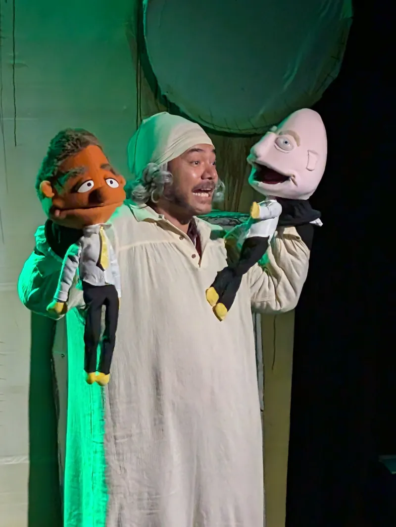 A performer with two puppets in A Christchurch Carol